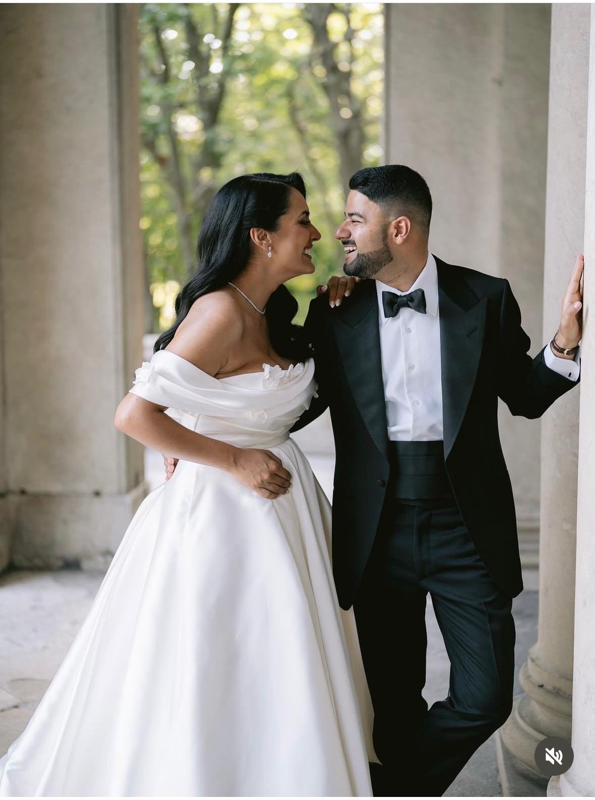 Bride and groom laughing together between stone columns, original photograph before it was turned into art